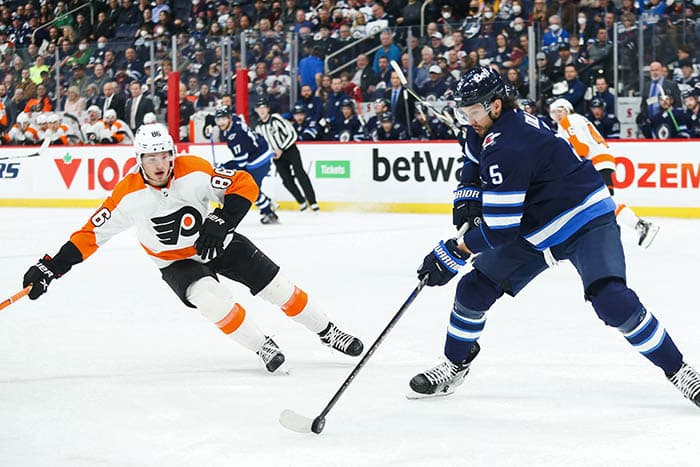 Winnipeg Jets defenseman Brenden Dillon (5) shields the puck from Philadelphia Flyers forward Noah Farabee (86) during the first period at Canada Life Centre. 