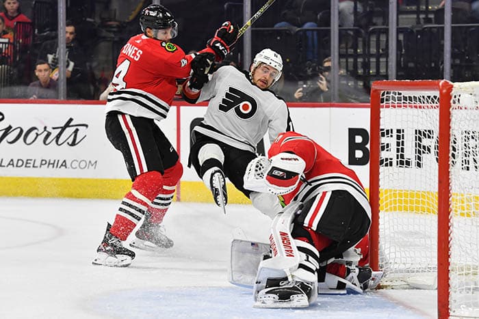 Philadelphia Flyers right wing Travis Konecny (11) is checked by Chicago Blackhawks defenseman Seth Jones (4) in front of goaltender Petr Mrazek (34) during the third period at Wells Fargo Center.