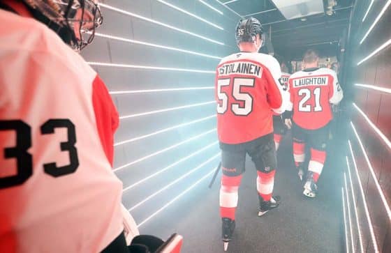 Samuel Ersson #33, Rasmus Ristolainen #55 and Scott Laughton #21 of the Philadelphia Flyers walk down the tunnel toward the ice surface for warm-ups against the Los Angeles Kings at the Wells Fargo Center on December 19, 2024 in Philadelphia, Pennsylvania.